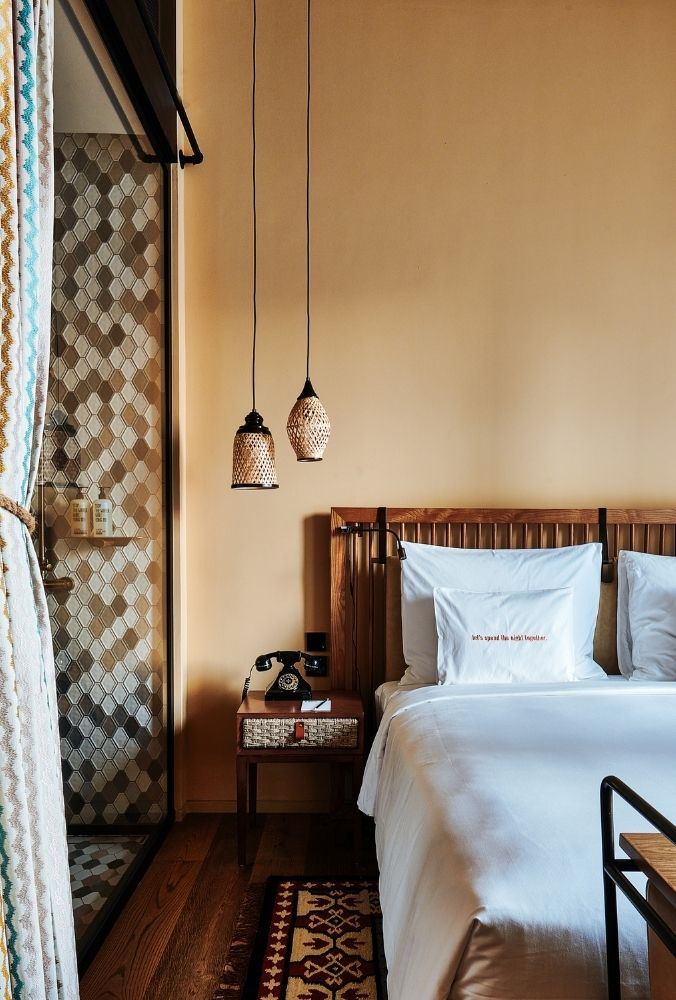 Guest room at 25hours Hotel One Central, Dubai, with a patterned headboard and a Moroccan rug